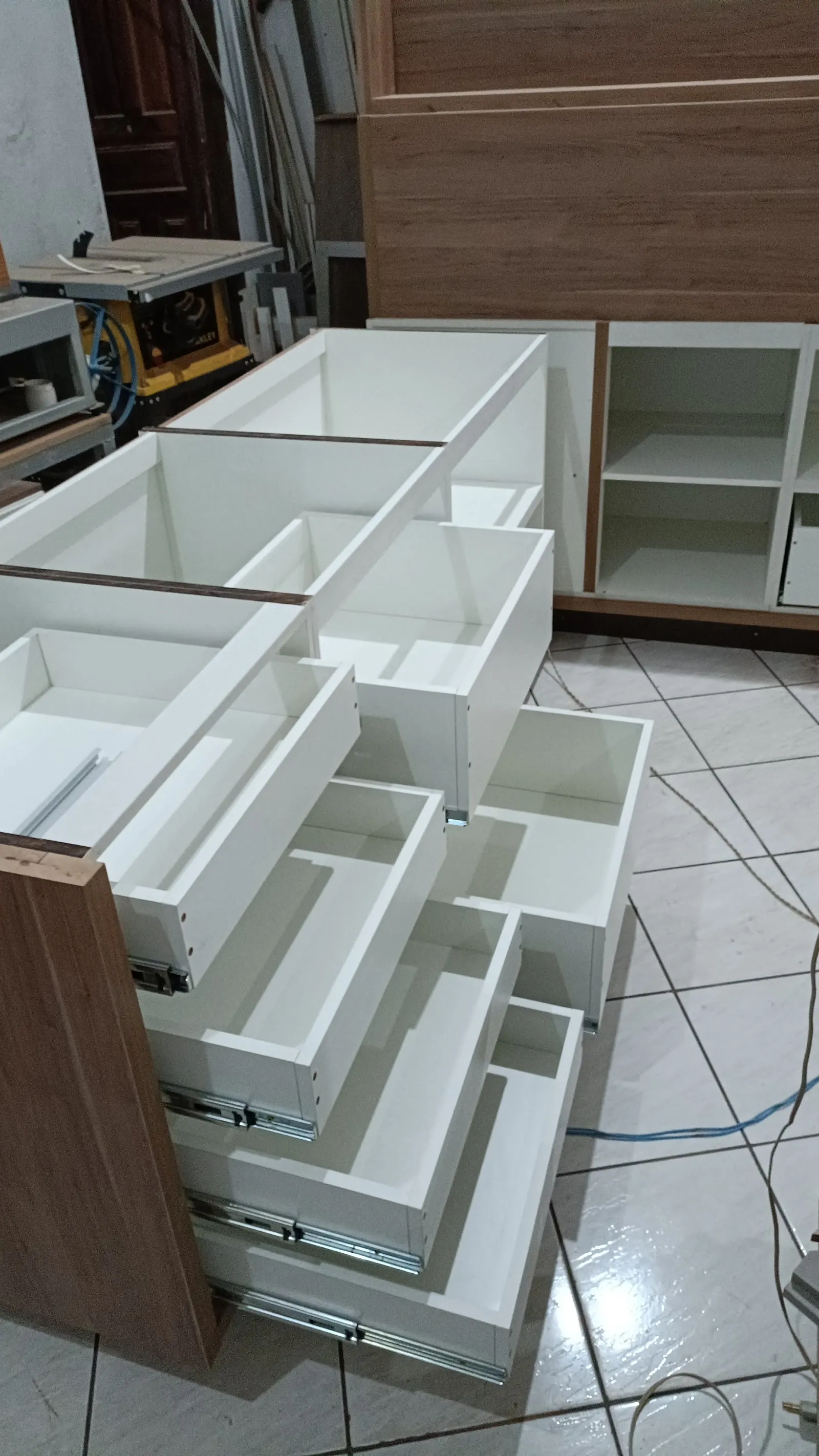 Gavetas e módulos brancos sendo produzidos na marcenaria