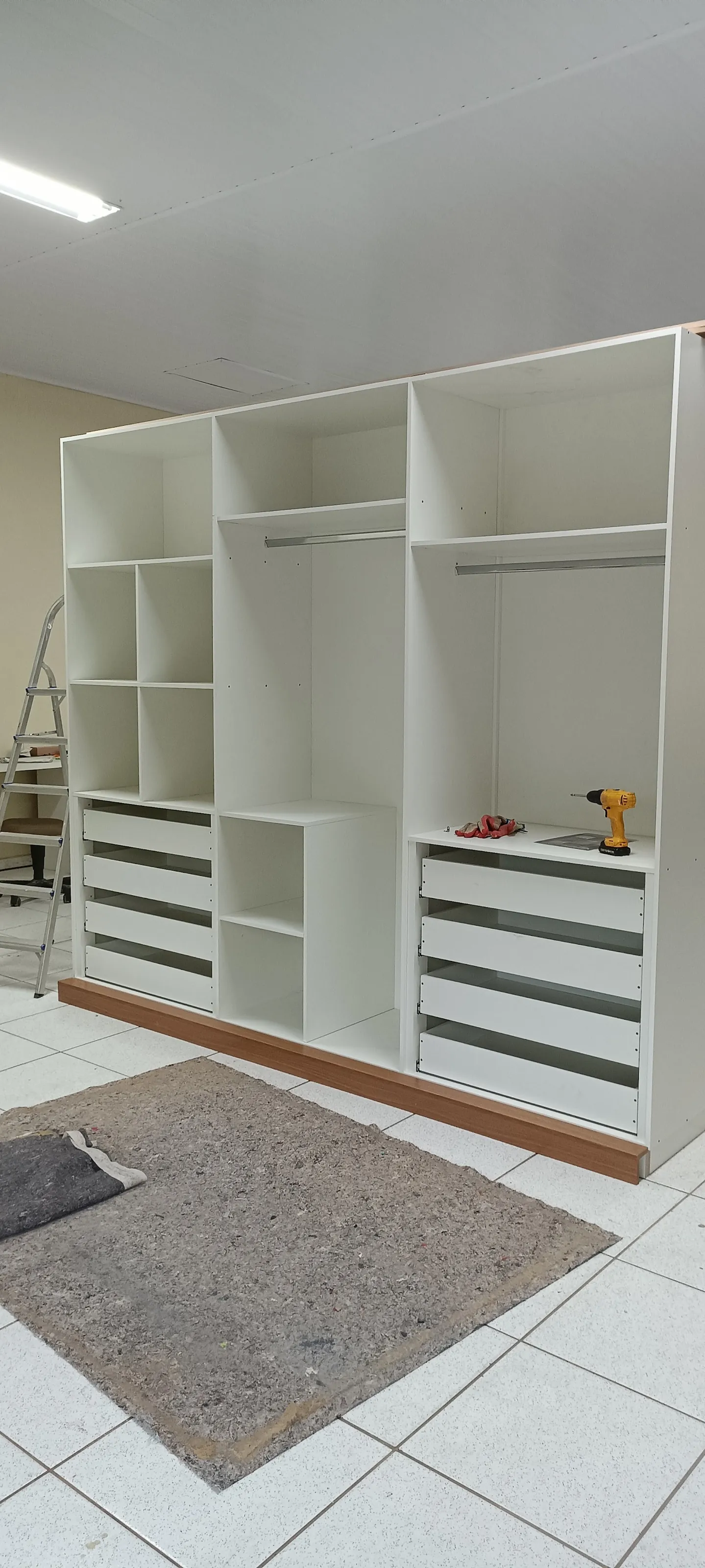 Guarda-roupa planejado branco com gaveteiro e cabideiros em montagem